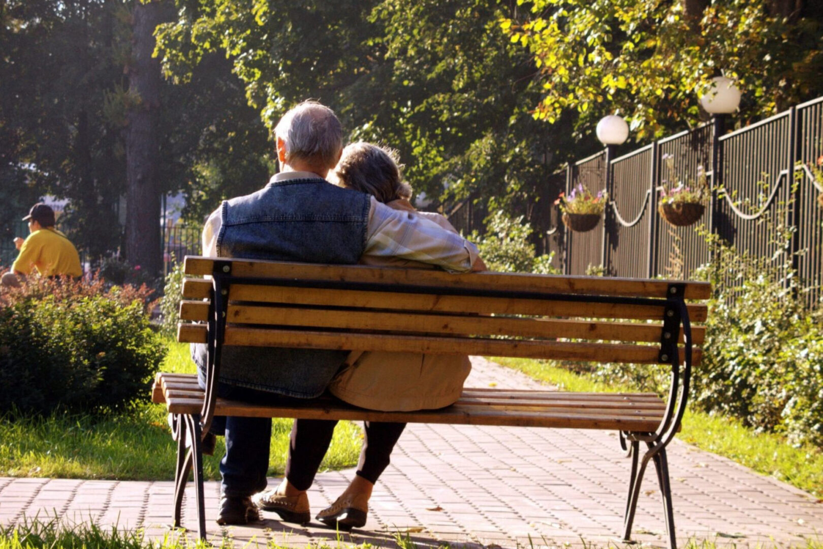 A man and woman sitting on top of a wooden bench.