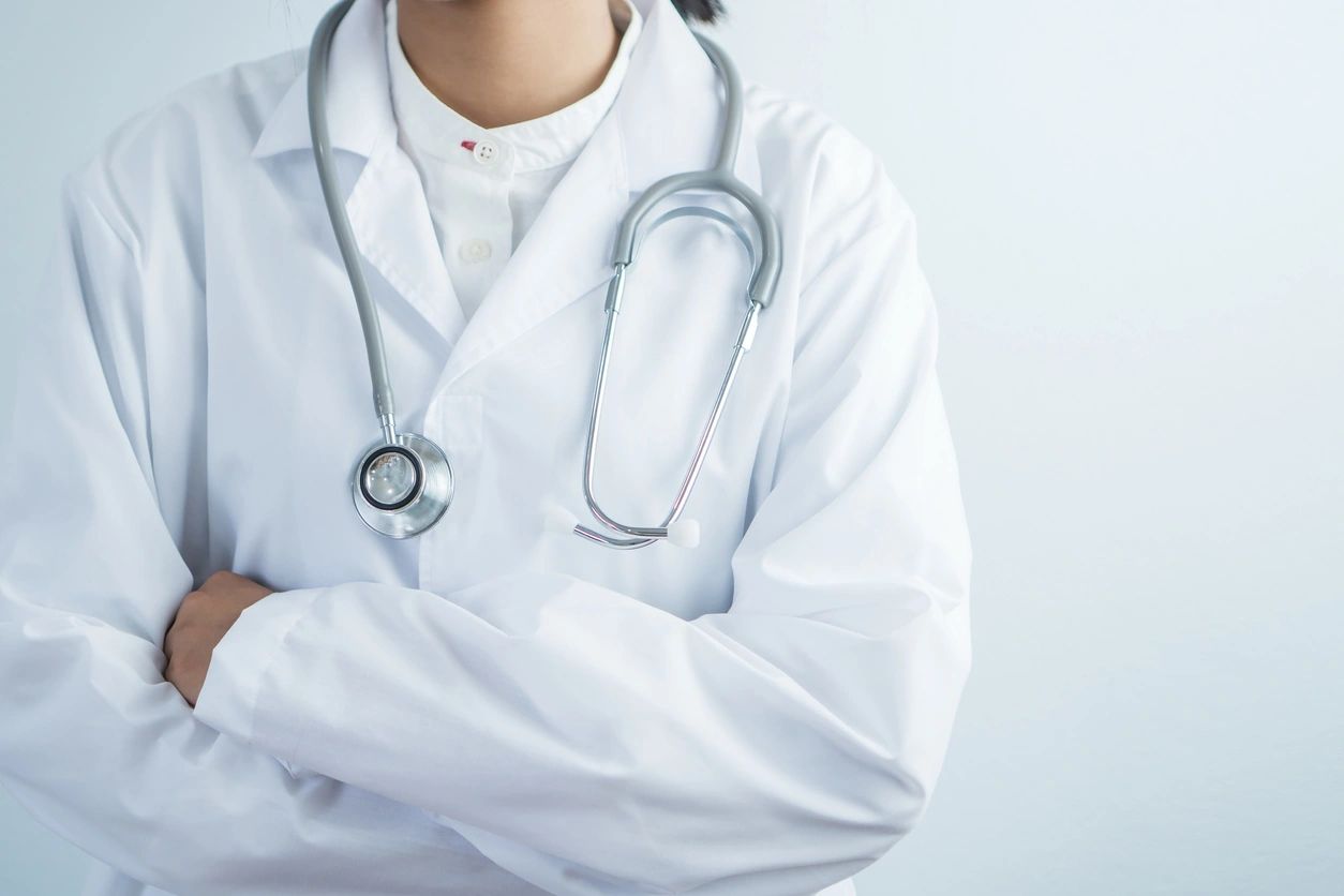 A doctor with his arms crossed wearing white lab coat and stethoscope.